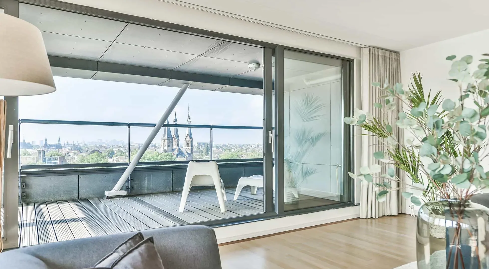 Modernes Wohnzimmer mit großen Aluminium-Schiebefenstern mit Blick auf eine Stadtlandschaft mit einer Kathedrale