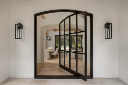 A large mirror adorns the entryway of a home complemented by a stylish pivot door nearby