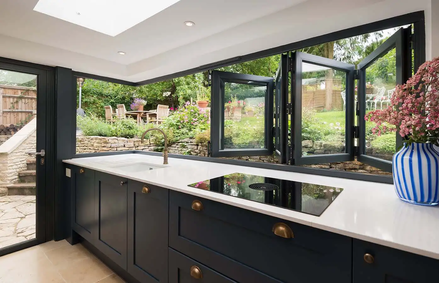 A modern kitchen featuring an aluminum window that opens to the outside enhancing natural light and ventilation