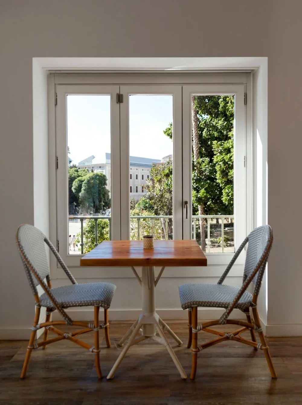 A table and chairs positioned in front of a casement window allowing natural light to illuminate the space