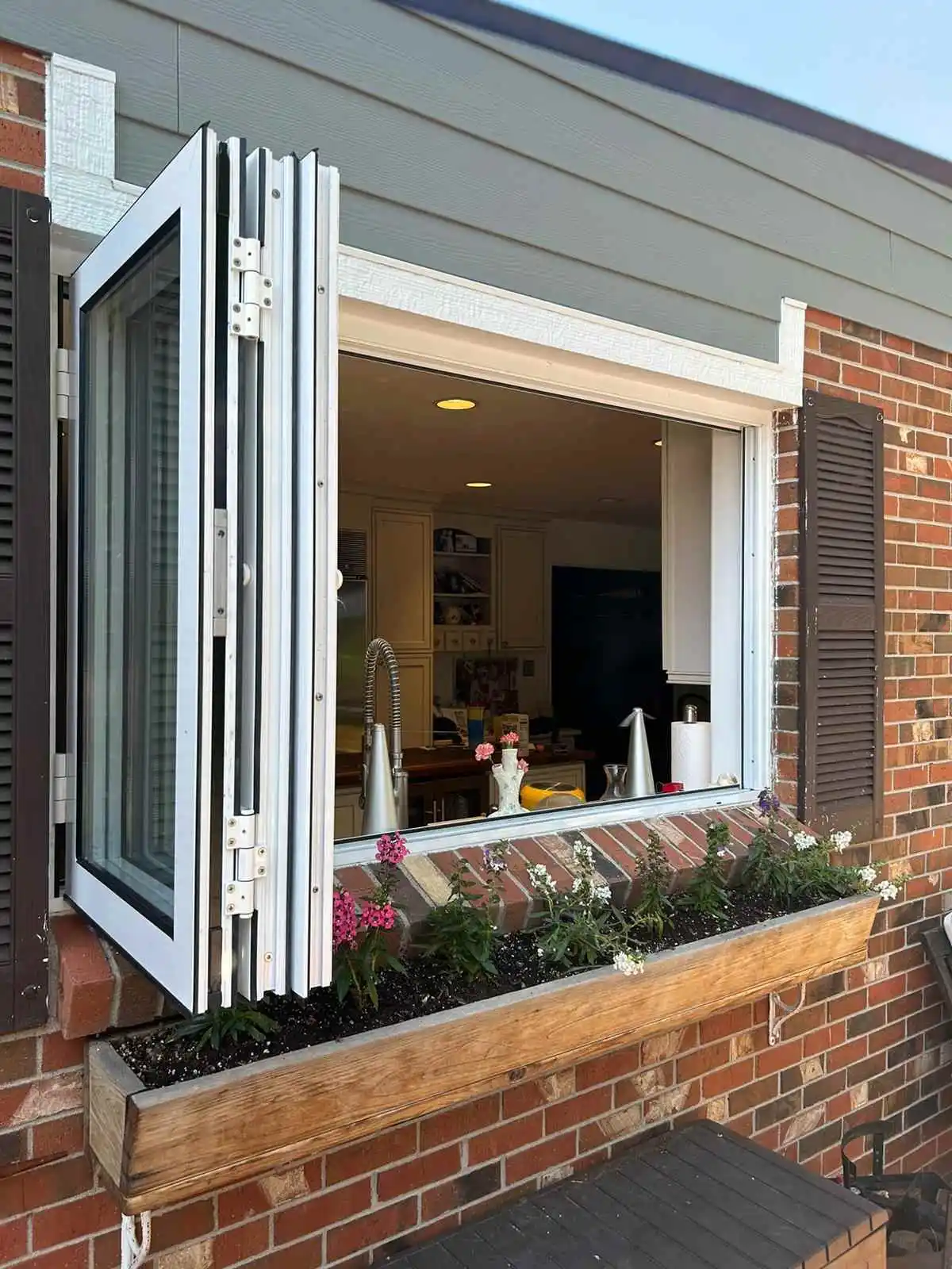 A window adorned with a planter is set against a brick building highlighting the quality of the best aluminum window manufacturer