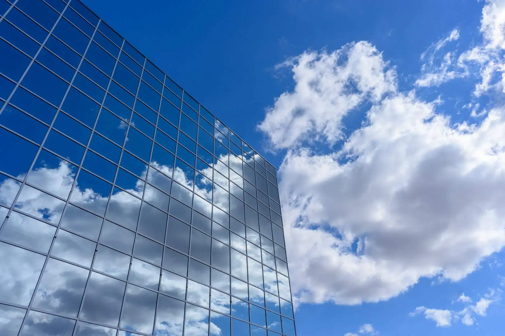 Reflection of clouds in a modern glass building showcasing the beauty of curtain wall architecture and its surroundings