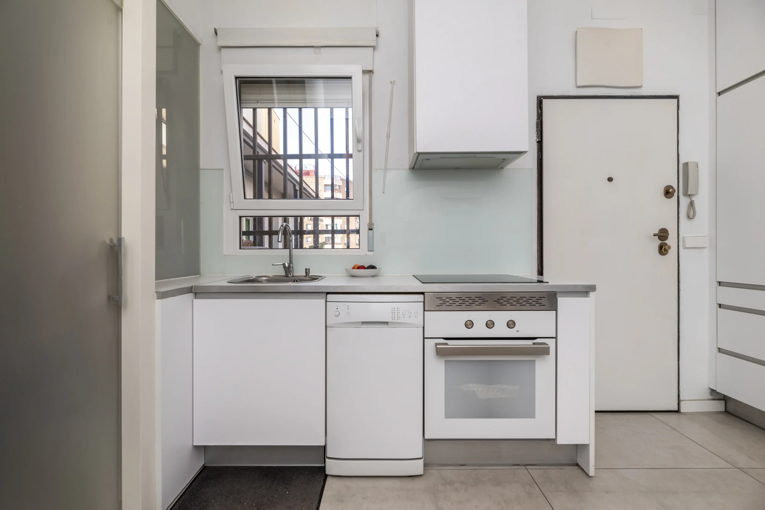 cocina pequeña apartamento estilo loft con muebles blancos rejas ventanas