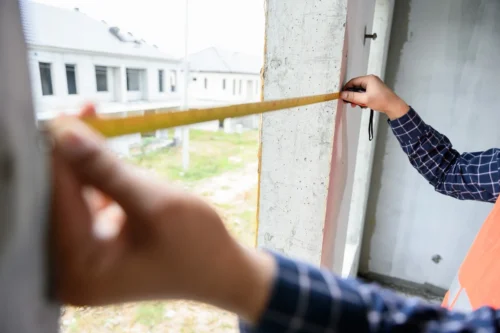 1 A man using a measuring tape to assess the height of a building preparing for an opening project