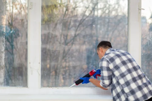 A man operates a power tool to clean a window ensuring additional weatherproofing for enhanced protection