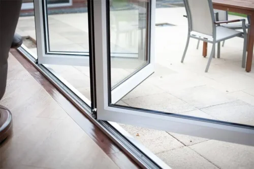 A patio area featuring a chair and table with bifold door tracks prepared and installed in the background