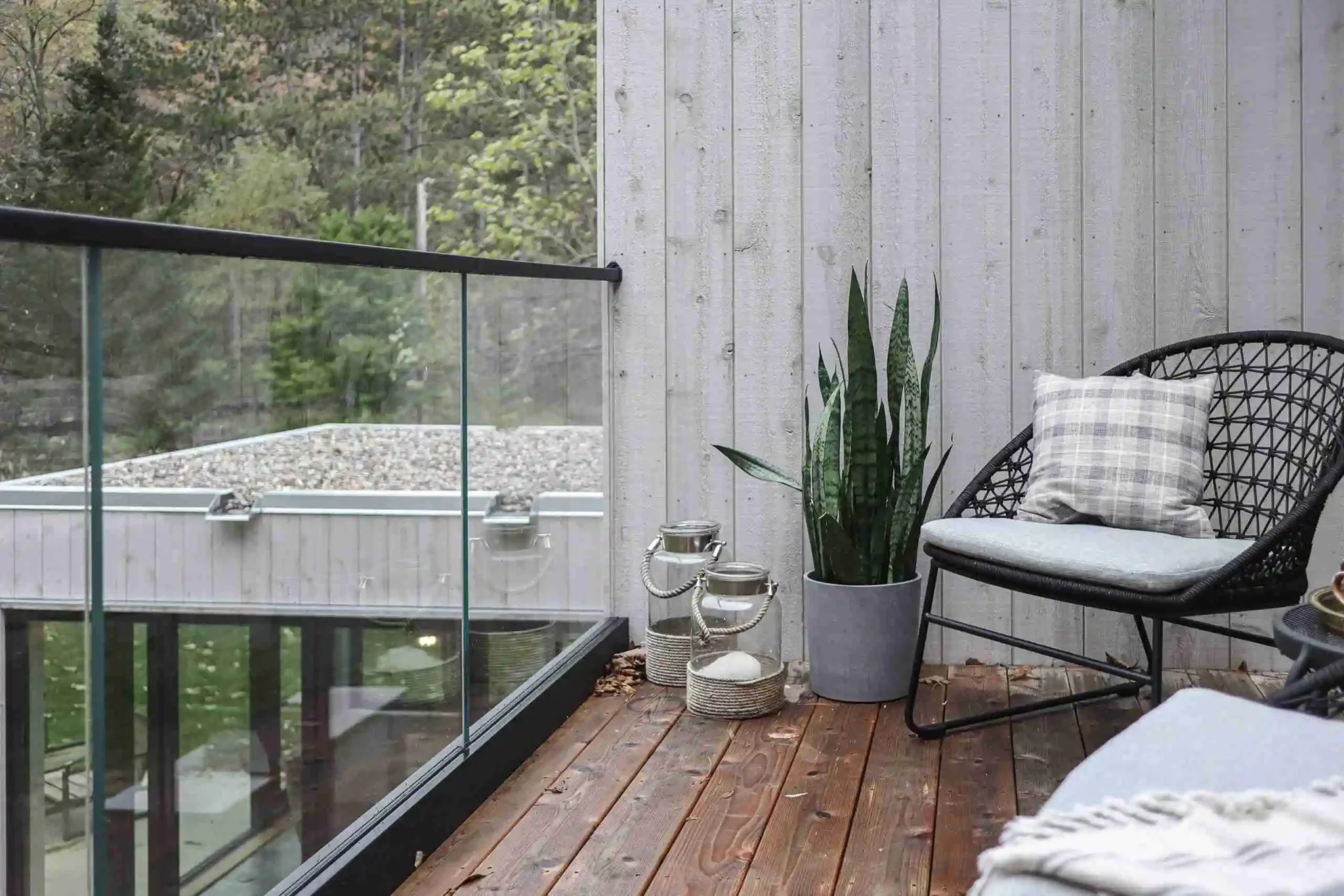 A balcony featuring a chair and a potted plant enclosed by a U Channel glass railing for a modern touch