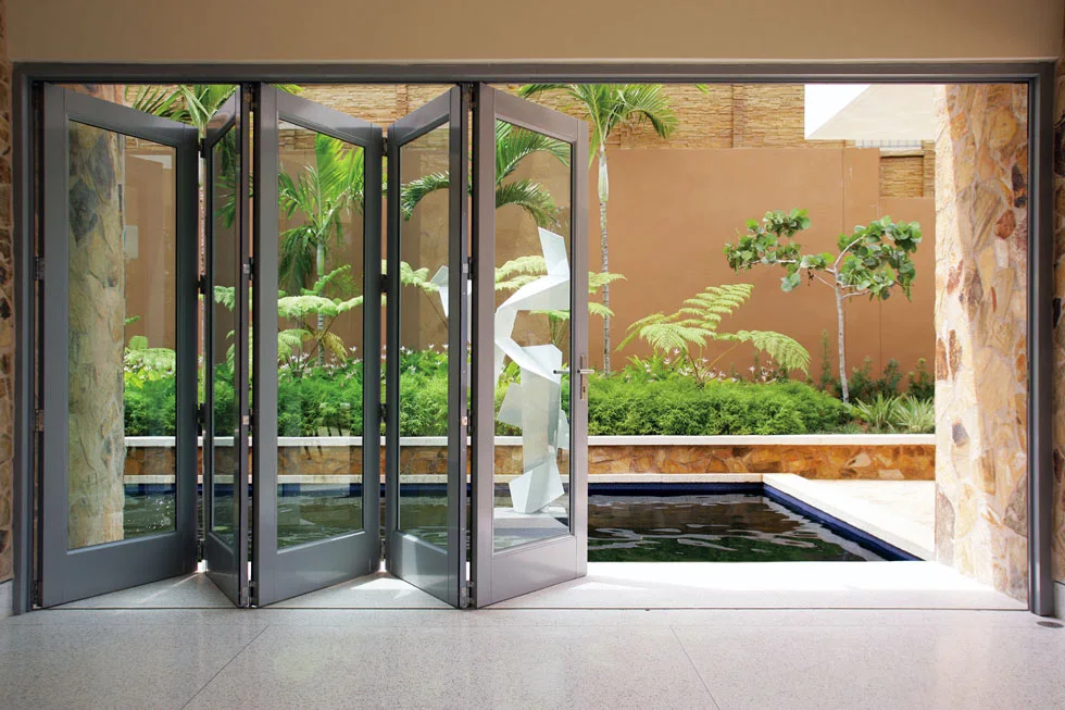 Una puerta de vidrio plegable se abre a un patio sereno con una hermosa fuente en el centro.