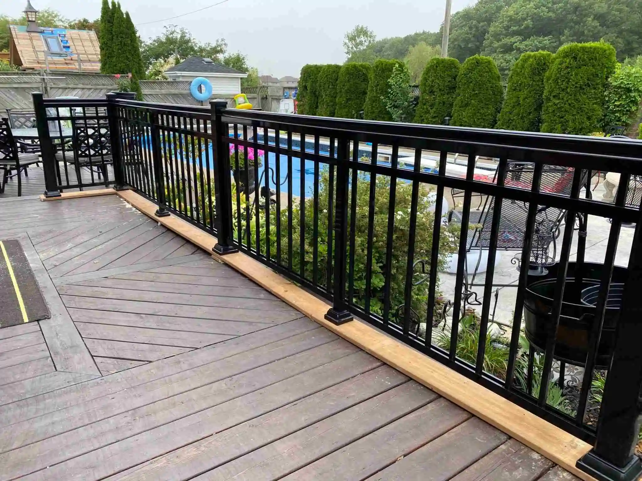 A deck featuring black aluminum railing and stylish chairs creating a modern outdoor seating area