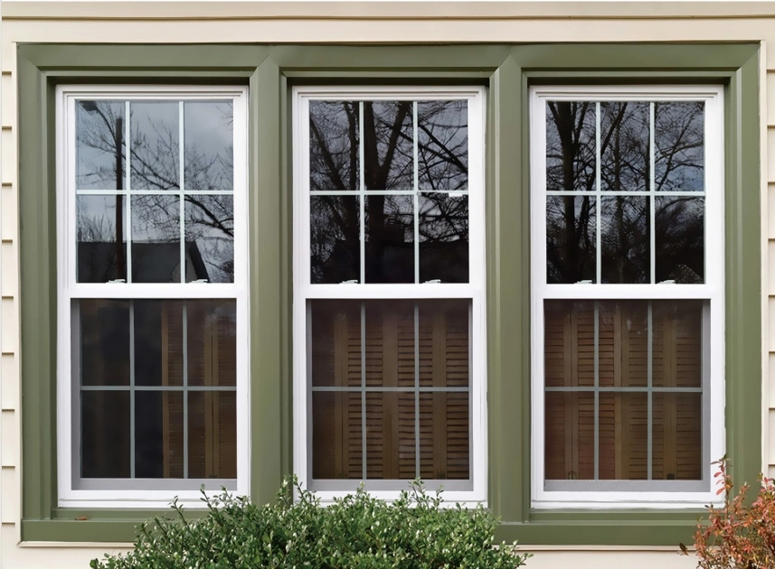 A hung window featuring green and brown trim showcasing a blend of colors in its elegant design