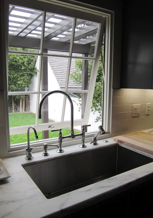 A kitchen sink beneath a window showcasing a window sill adorned with decorative items and natural light streaming in