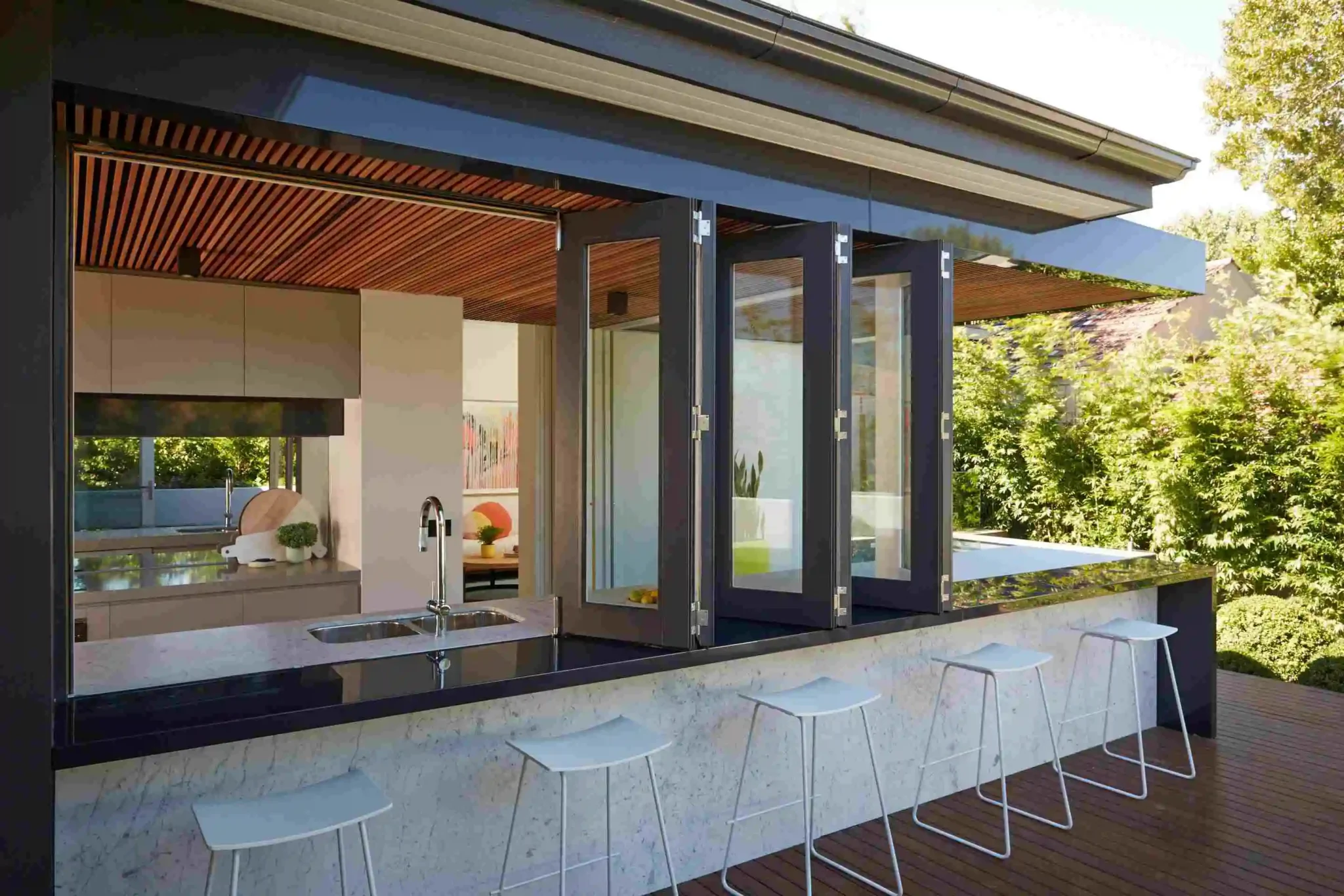 A modern kitchen featuring a bar area and a large bi fold window that enhances natural light and outdoor views