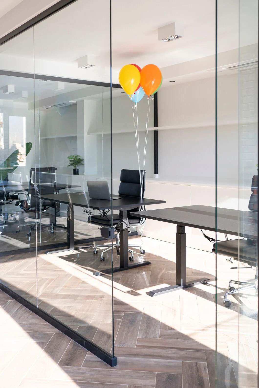 A modern office featuring frameless glass partitions with a table and chairs arranged for collaboration