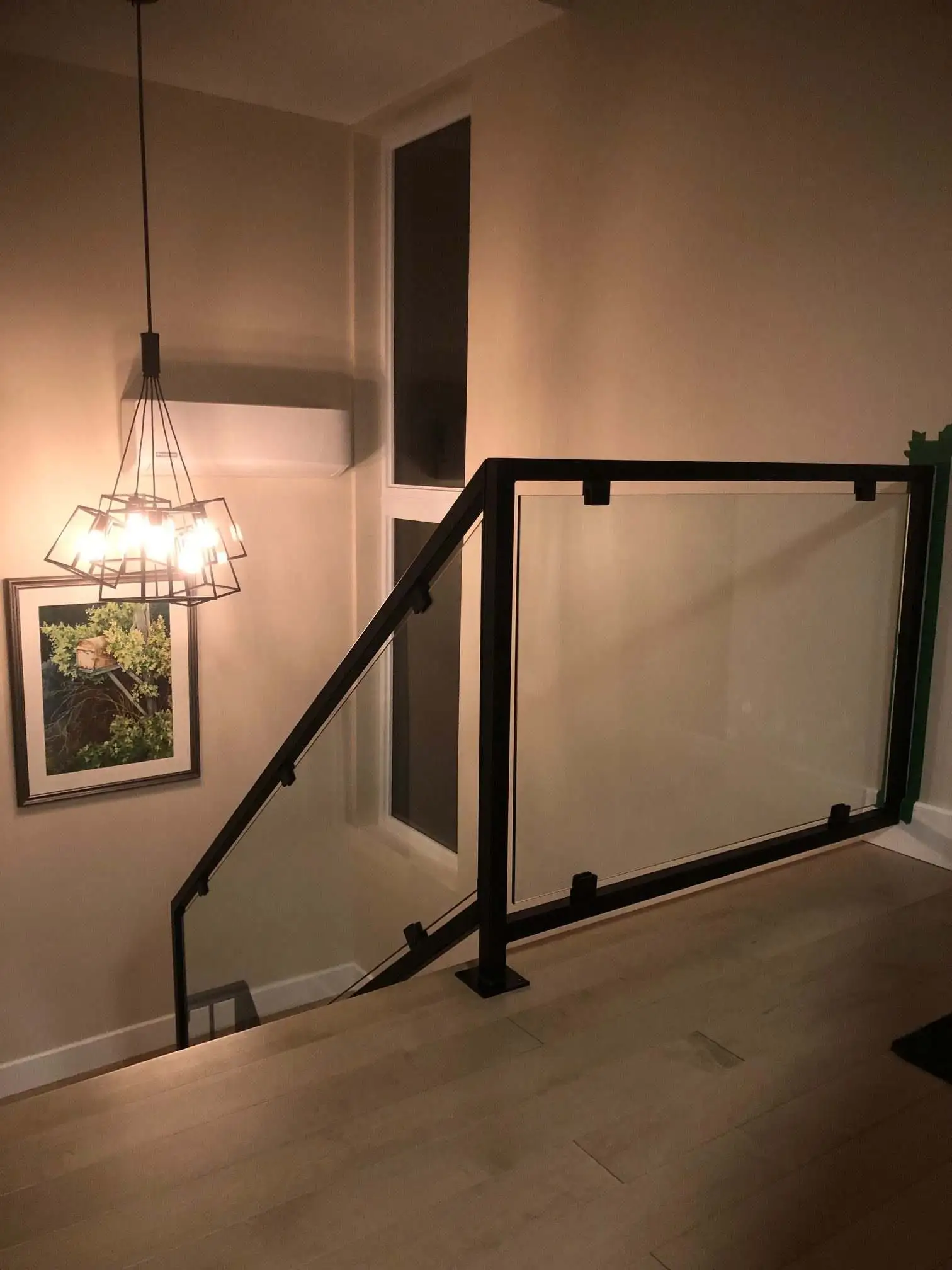 A modern room featuring a sleek aluminum glass railing and an elegant light fixture overhead