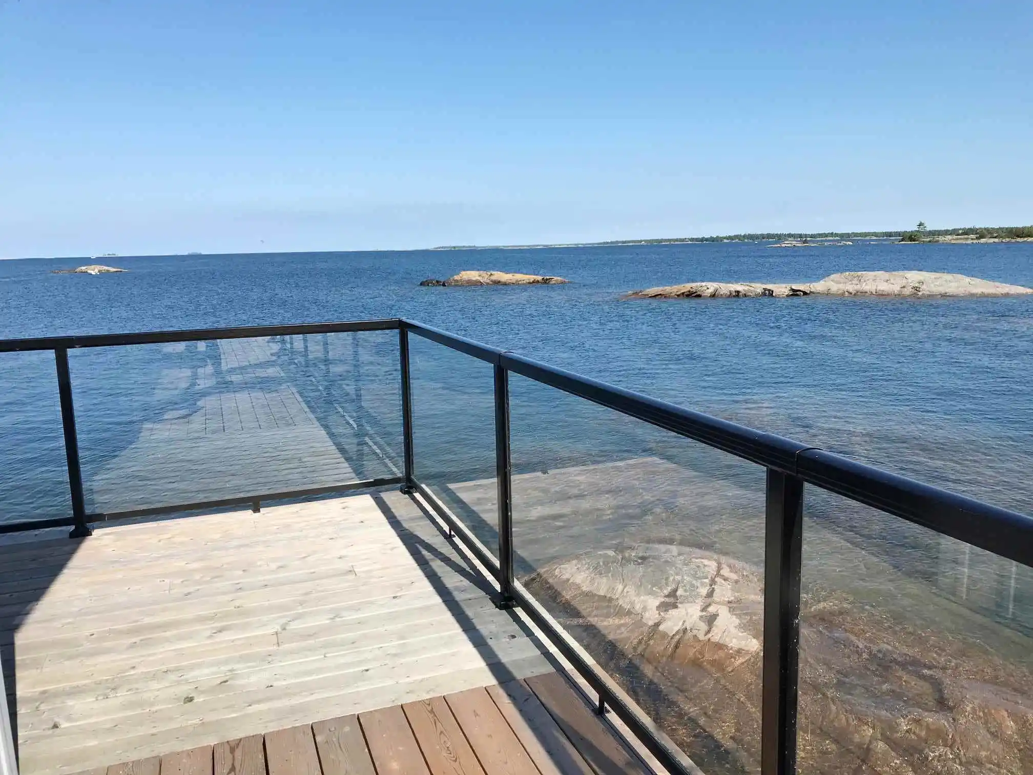 A scenic deck with an aluminum glass railing offering a stunning view of the tranquil water below