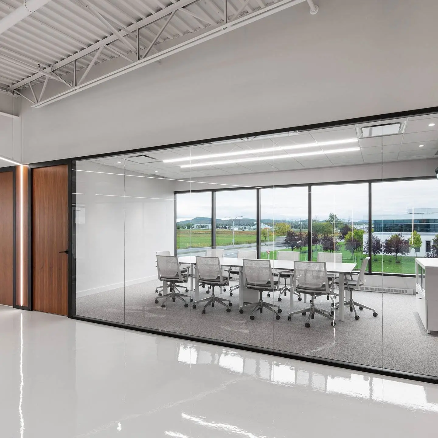 Contemporary office space with frameless glass partitions and a large conference room designed for transparency and teamwork