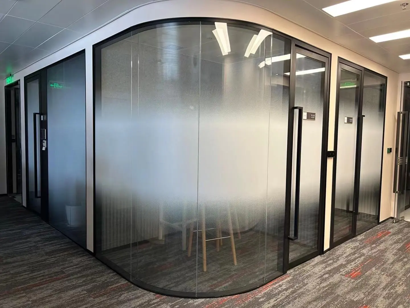 Frameless glass partition in an office featuring a sleek door enhancing the modern workspaces aesthetic and functionality