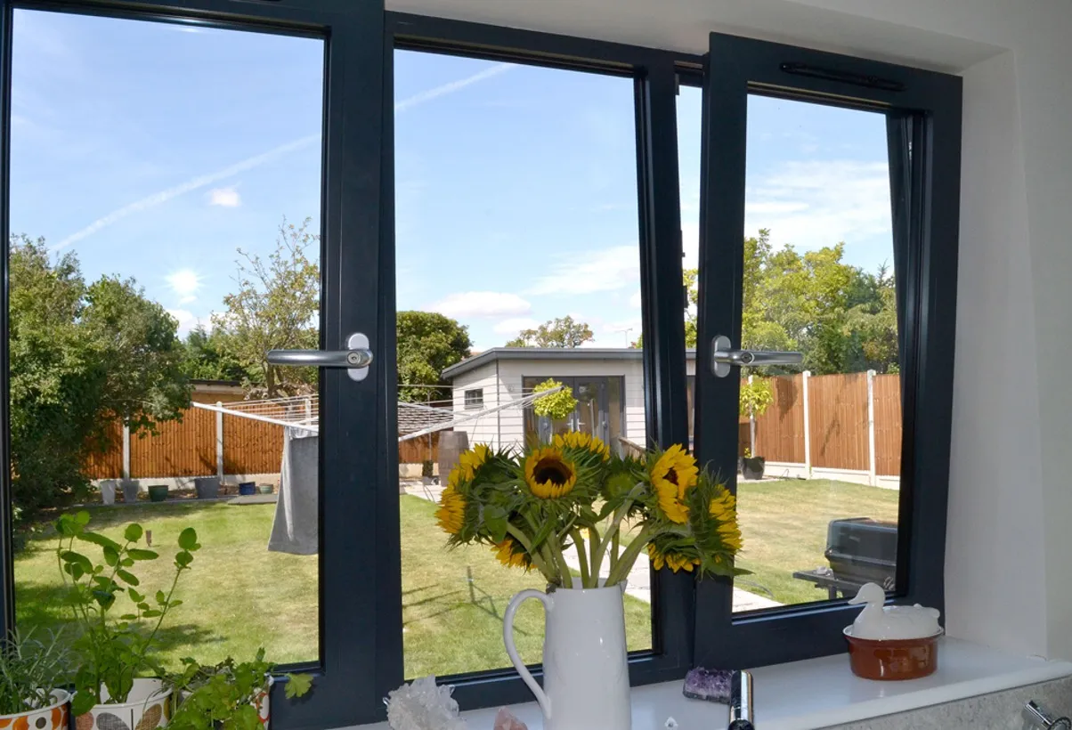 Blick auf Sonnenblumen durch einen modernen schwarzen Aluminiumfensterrahmen