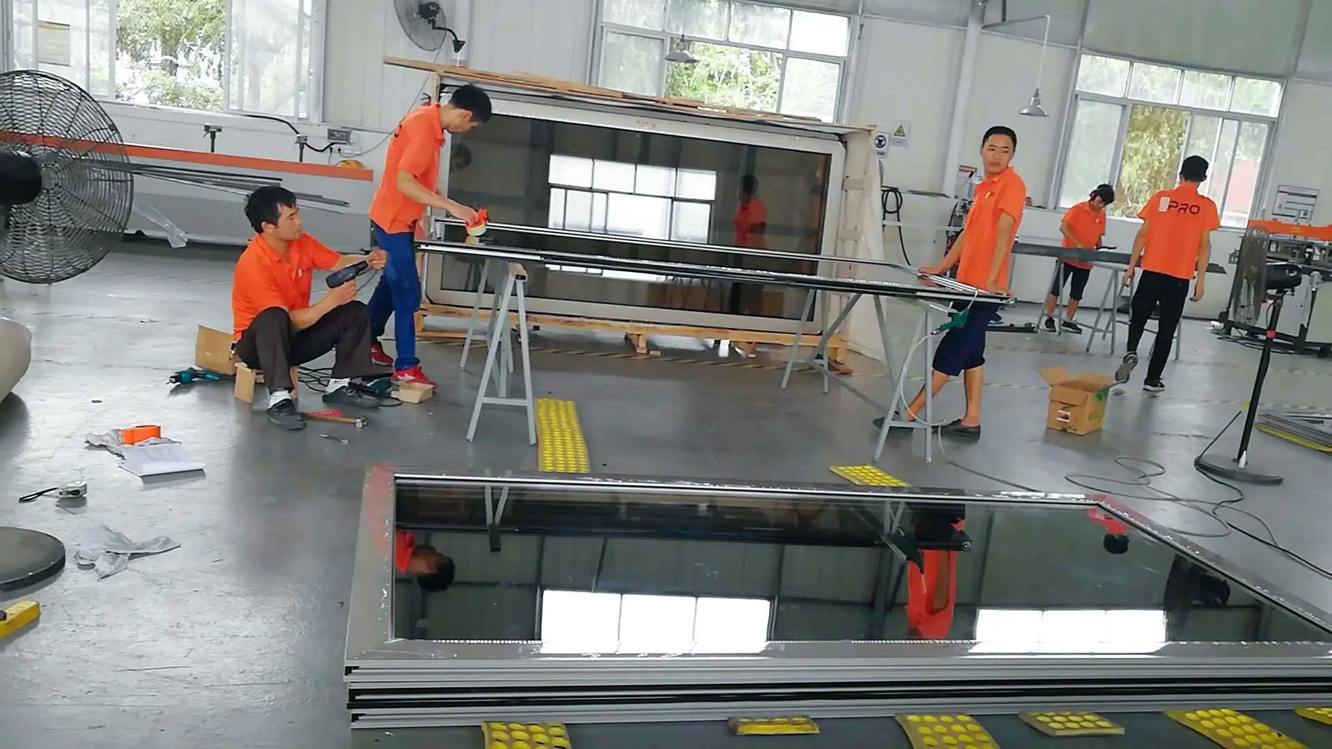 Team assembling large glass panels in a factory space