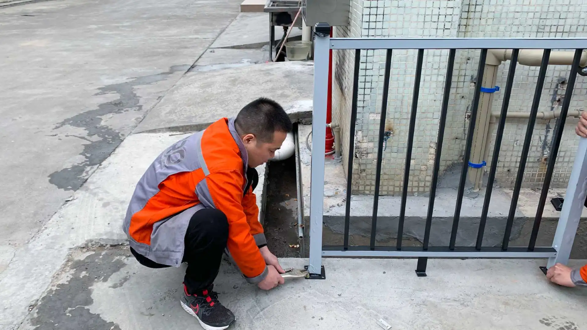 Technician installing a small metal fence on concrete