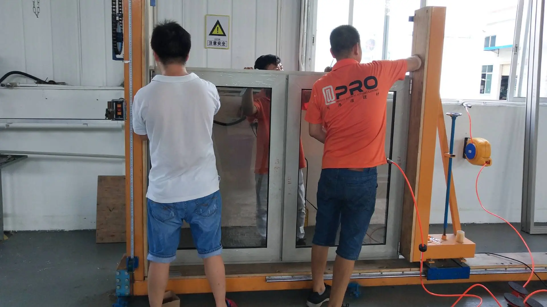 Three workers assembling a large glass door frame