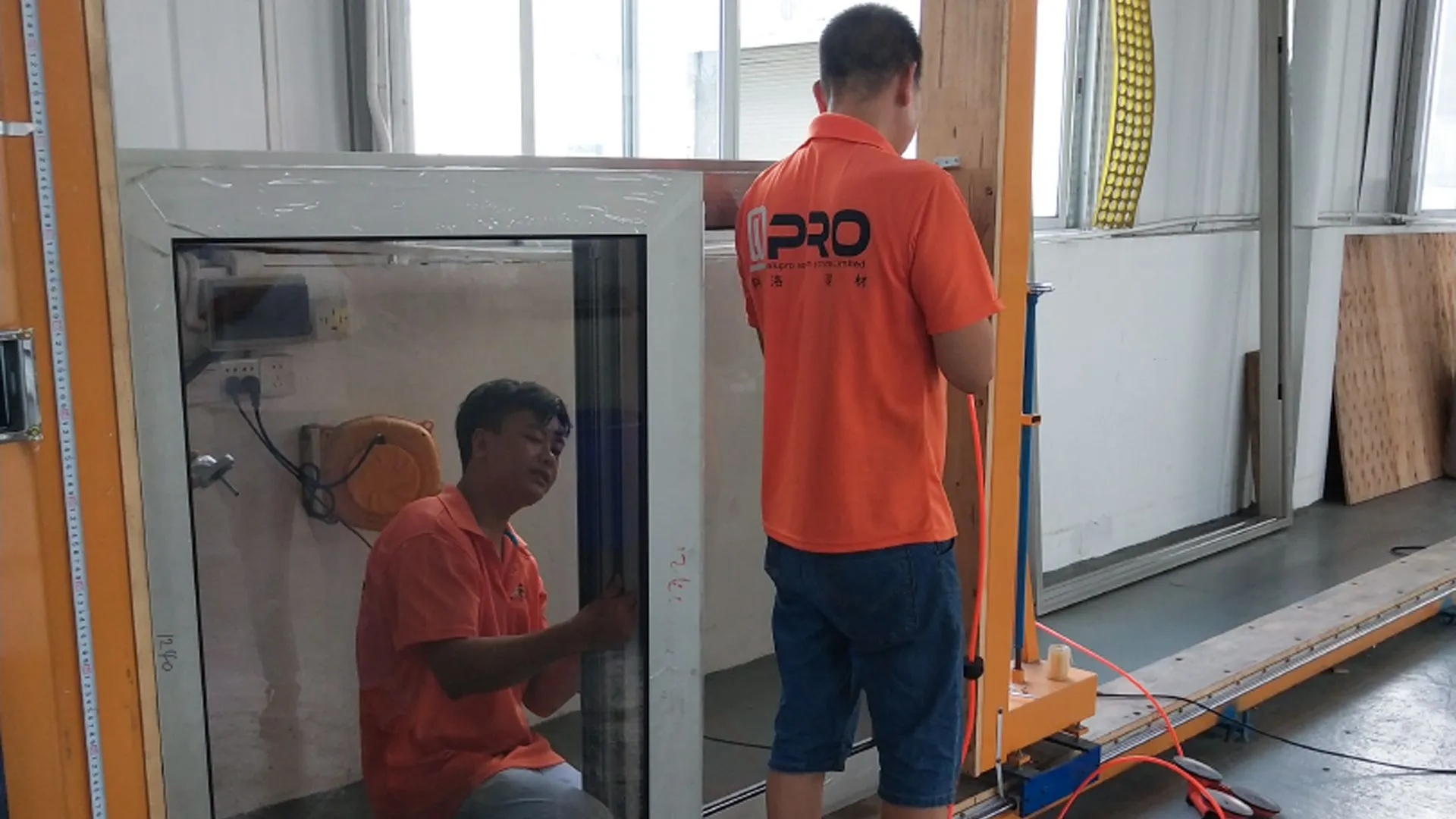 Two workers fixing a sliding glass door in a workshop