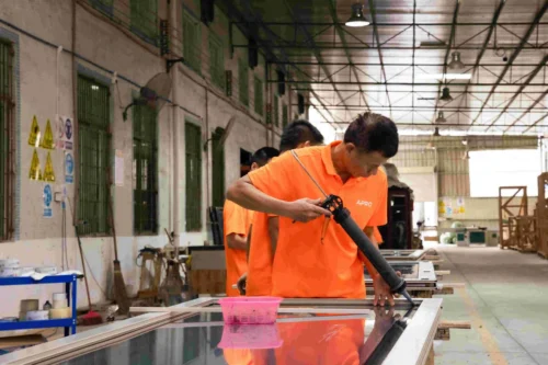 Un lavoratore che applica il sigillante al telaio di una porta per l'isolamento