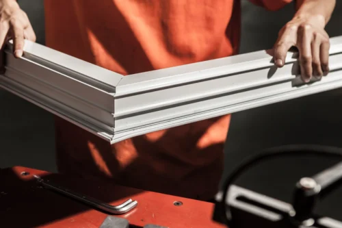 A worker assembling an aluminium door frame with precision