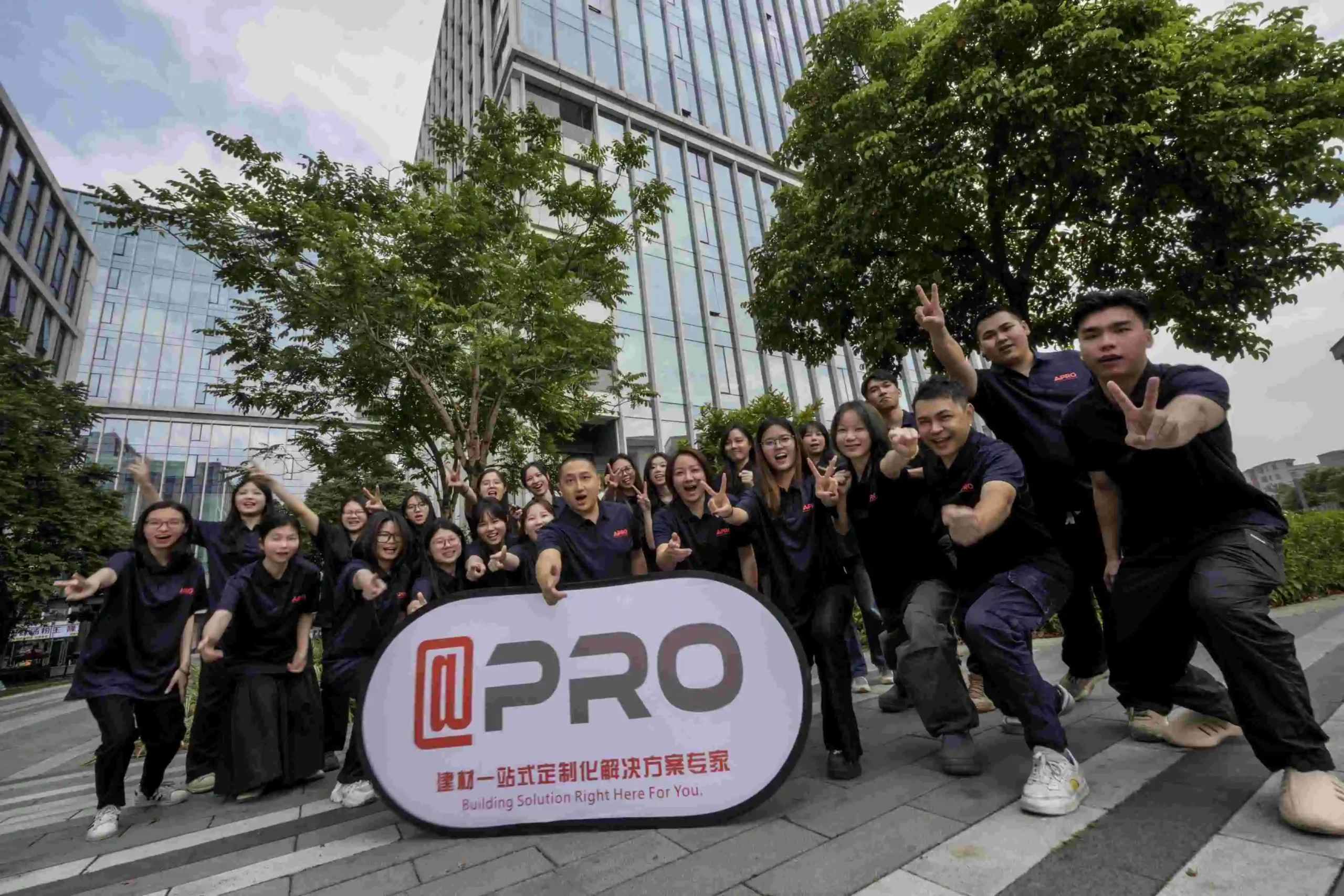 APRO team celebrating outdoors with company banner in modern setting