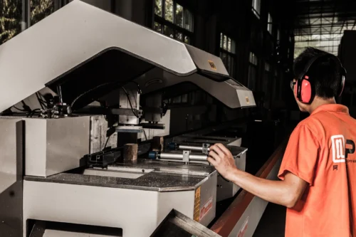 Employee overseeing an advanced cutting machine in a production workshop