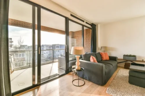 Living room with floor to ceiling aluminium sliding doors leading to a balcony