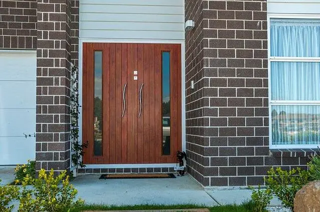 Porta externa padrão moderna com painéis de vidro verticais com acabamento em madeira e maçanetas elegantes de aço inoxidável