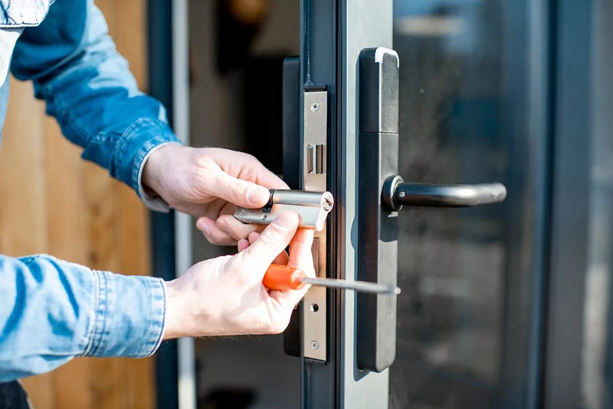 Person repairing a modern glass door lock with tools