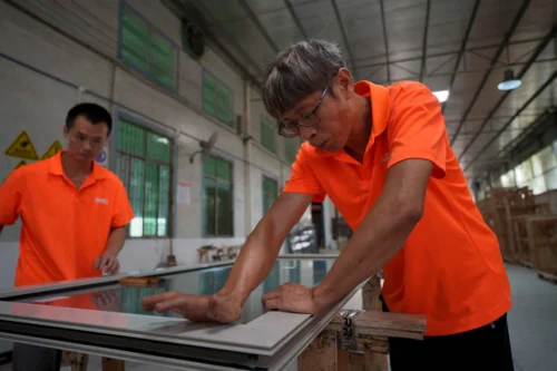 Skilled workers fitting glass into window frames for precision and quality