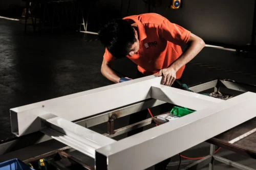 Technician attaching hardware components to an aluminium door frame