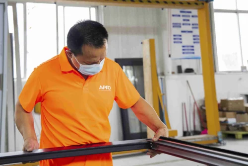 Technician fitting glass pane into aluminum frame