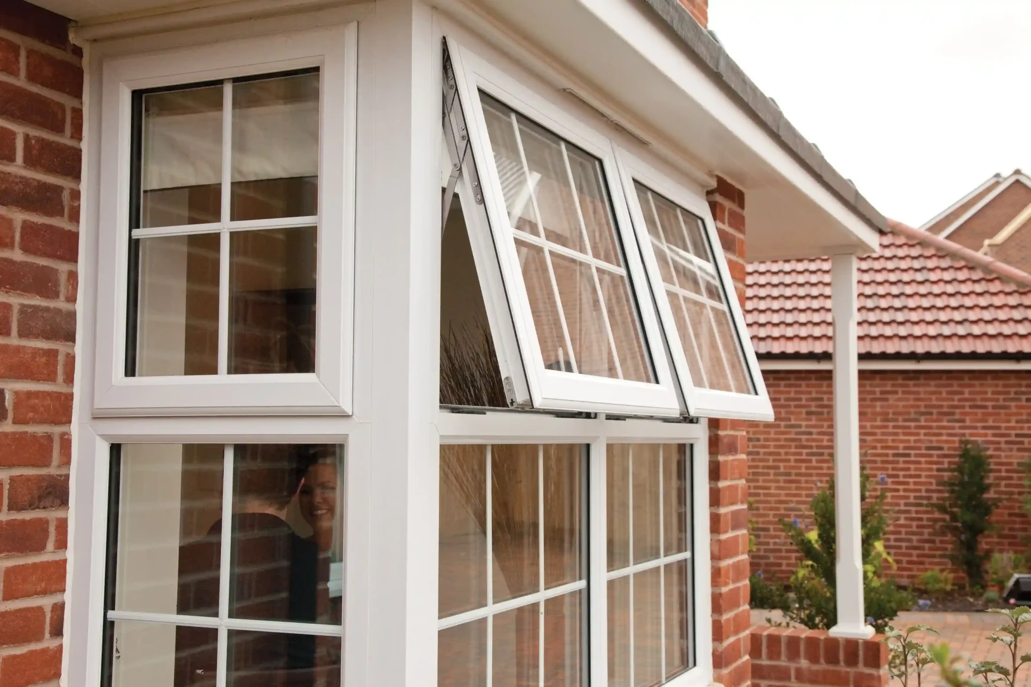 White Awning Window with Grid Design on a Red Brick House