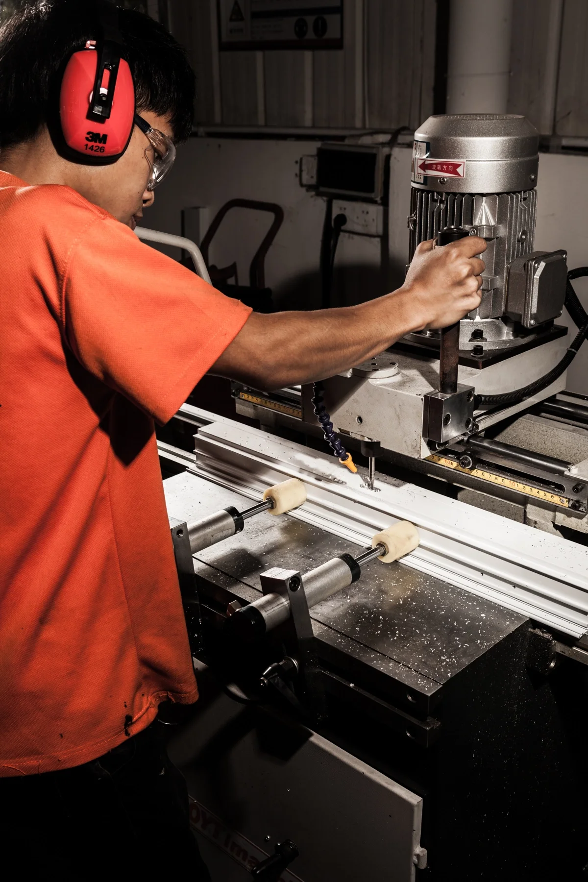 Worker operating a precision drilling machine in a manufacturing facility