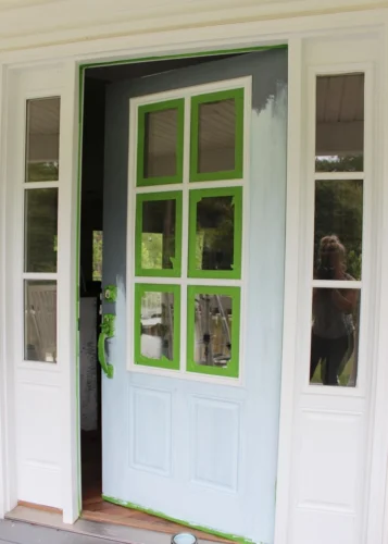 A partially painted front door with taped glass panes