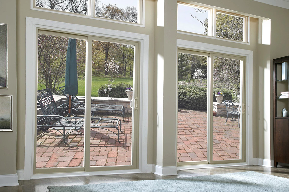 Bright living room with large vinyl sliding patio doors overlooking a garden patio