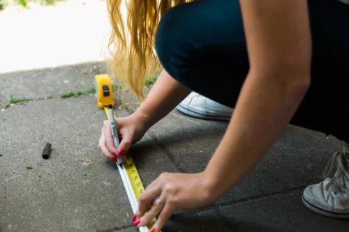 Person measuring a surface with a tape measure outdoors