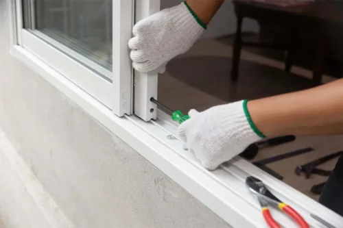 Trabajador ajustando un marco de puerta corrediza con un destornillador