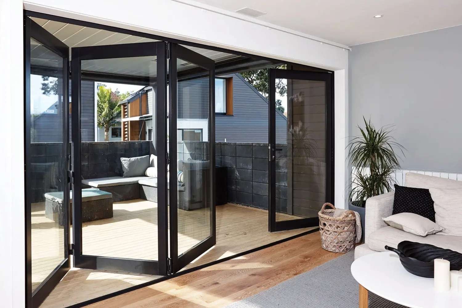 Puertas plegables modernas de aluminio negro que conectan una sala de estar con una terraza.