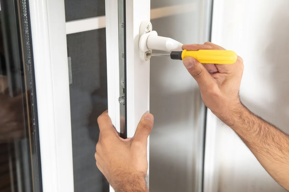 A person installs a window lock with a screwdriver