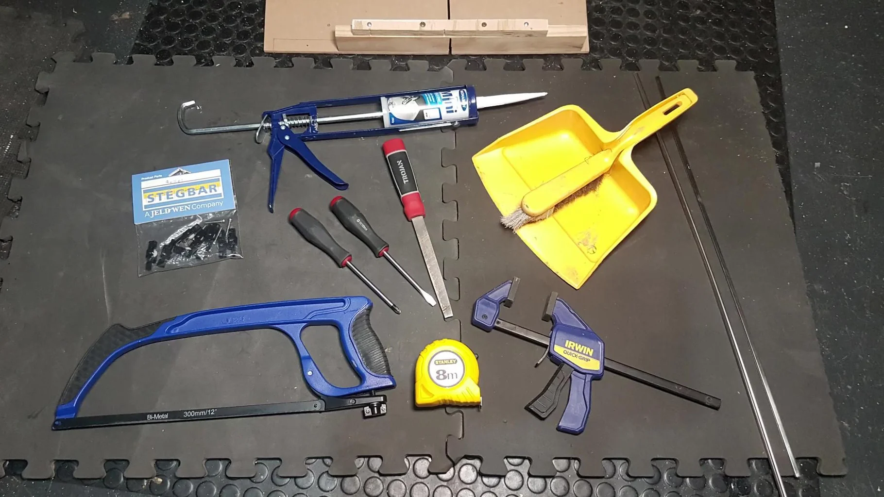 Various tools laid out on a work surface including a saw