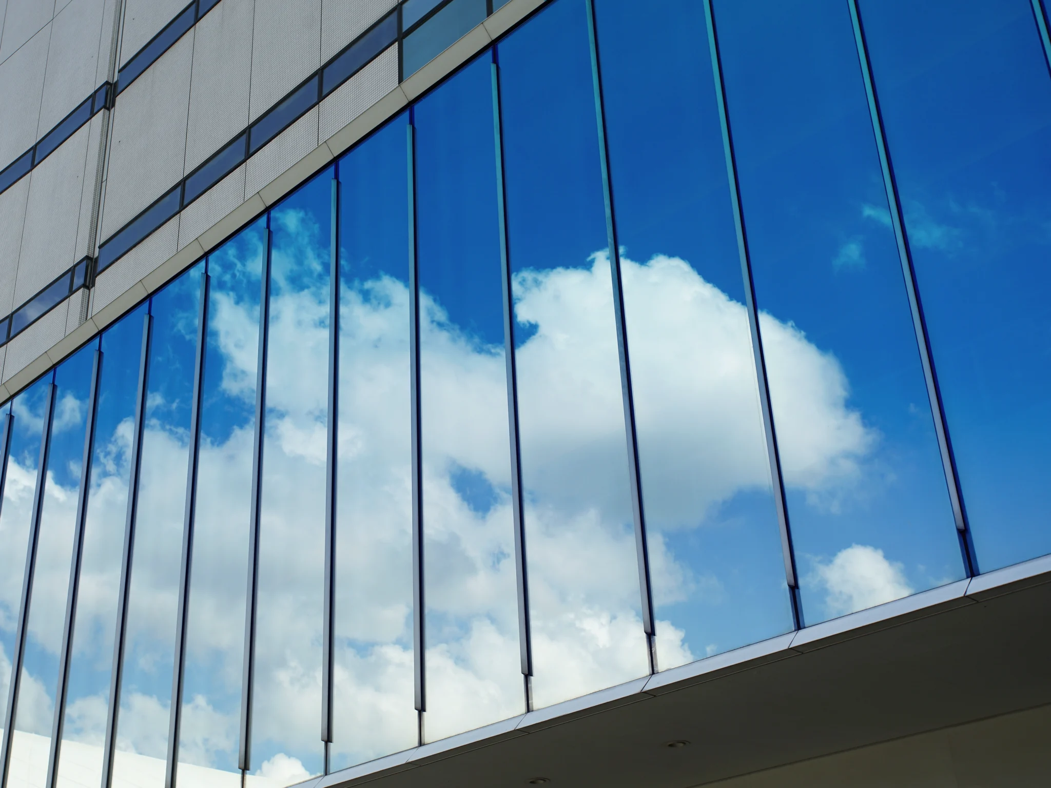 Um grande edifício com paredes de vidro e uma janela proeminente exibindo um design de parede cortina invisível