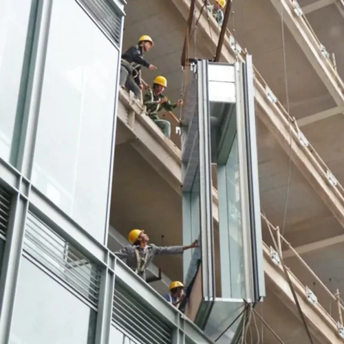 Workers are hoisting the unitized curtain wall into place