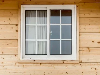 A sliding window with a white frame set in a wooden house showcasing a blend of natural and modern design elements